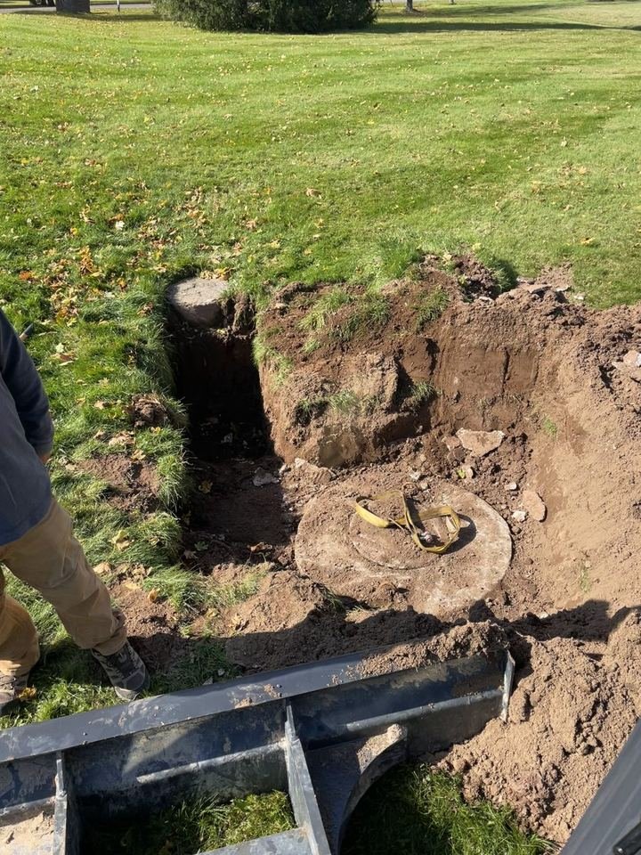 Excavation beside a lawn in Cocagne, NB, exposing the buried septic pump chamber lid